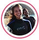 Profile image of reviewer, a young woman in wetsuit smiling on a windy beach.