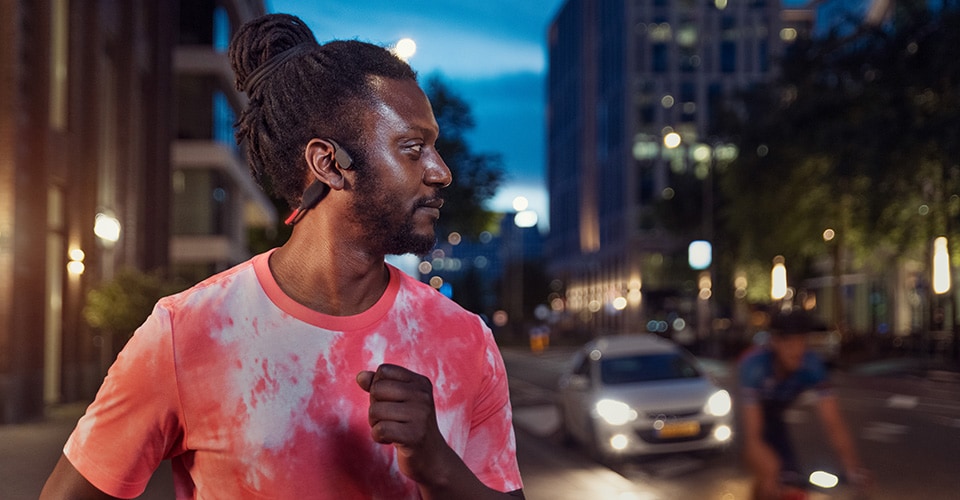 Athlete using bone conduction headphones on a busy street