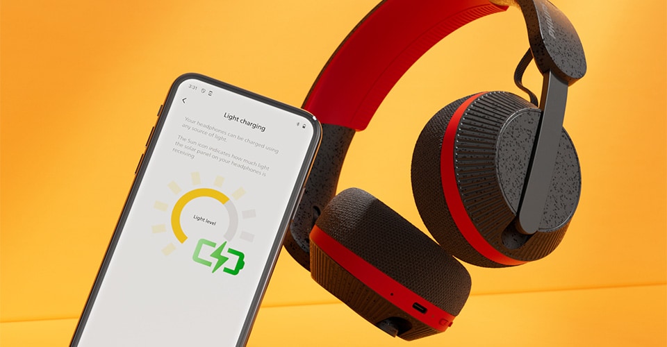 Philips A6219 headphones next to a smartphone displaying the light charging screen, against a bright orange background