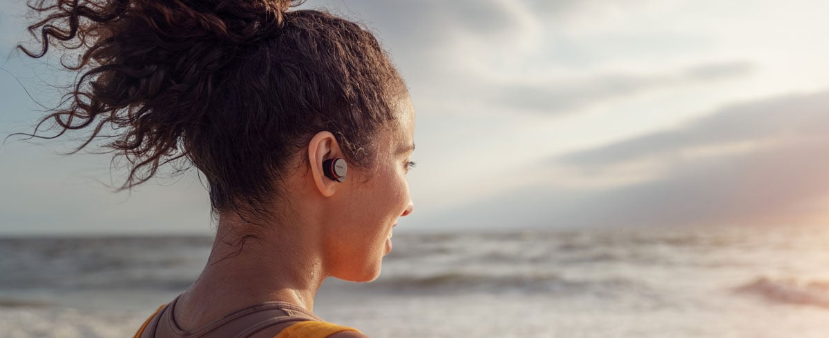 Women using true wireless headphones on the seaside