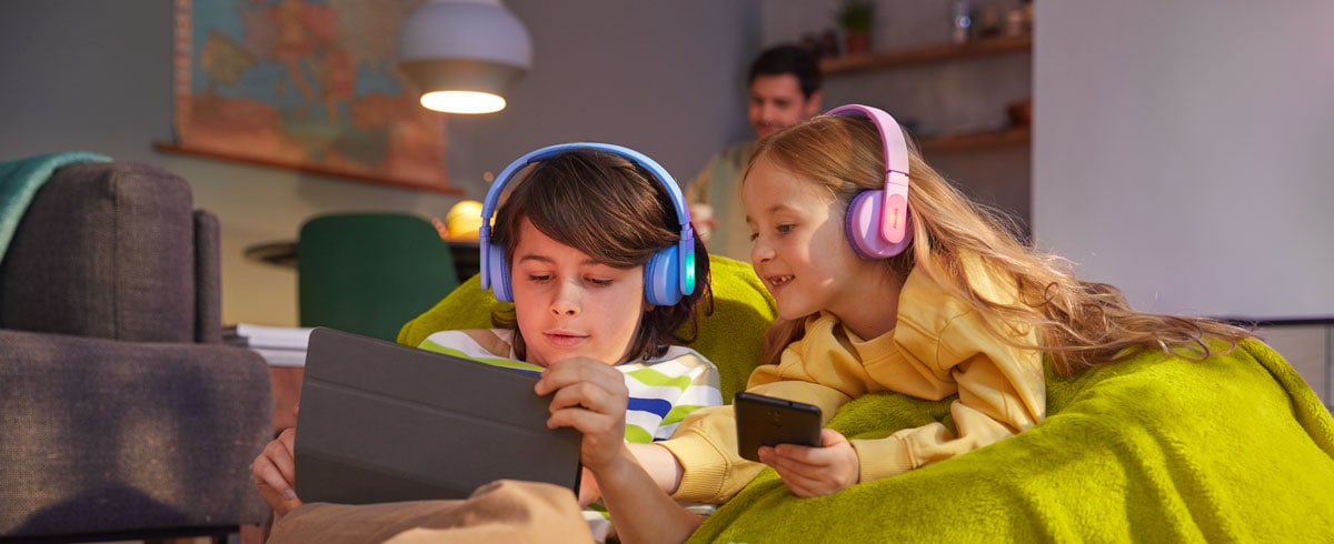 A boy and a girl using their devices while using durable kids headphones