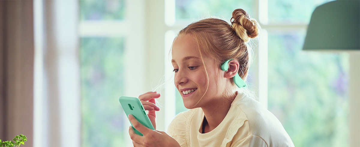 A girl using green bone conduction kids headphones