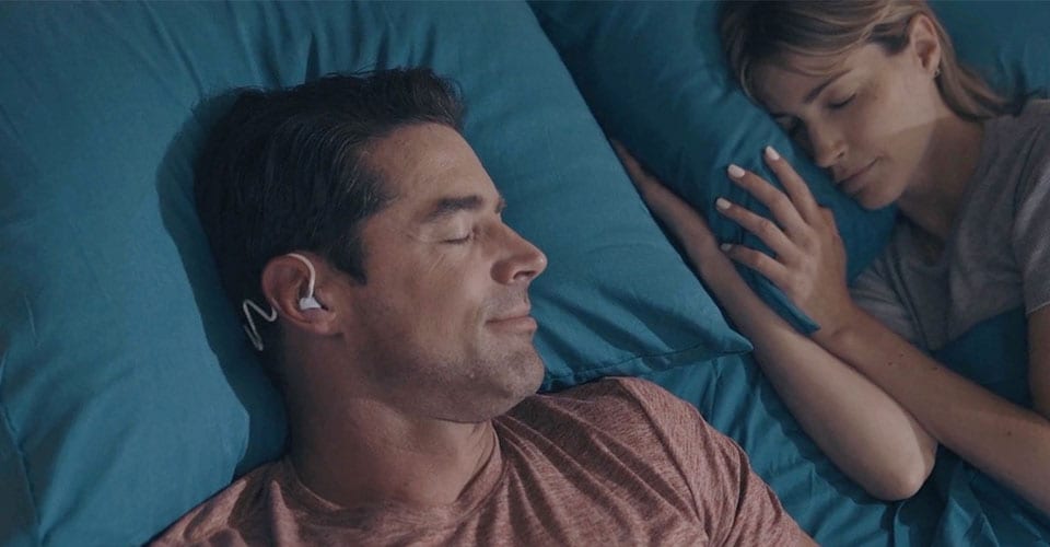 Image of a man sleeping with Philips Sleep Headphones in to avoid disturbances while sharing a bed with a partner..