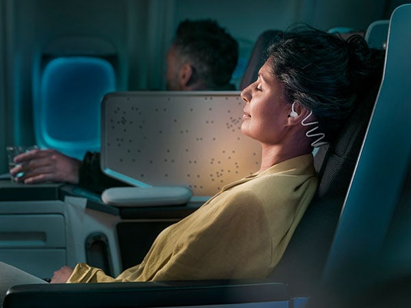 Woman sleeping on airplane while using Philips tan7808 sleep headphones