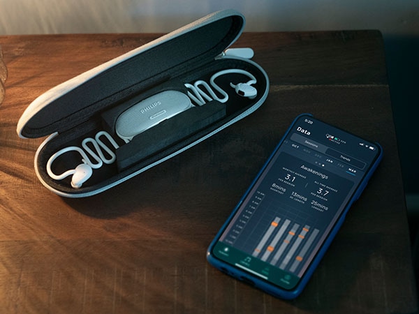 Philips TAN7808 sleep headphones in its case with Kakoon app displaying sleep data