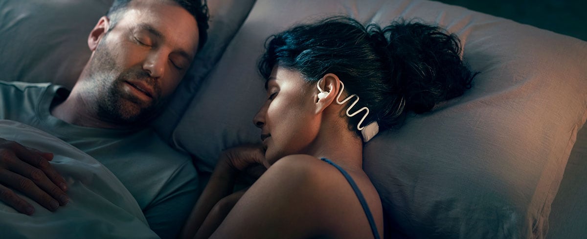 Woman sleeping with husband while wearing Philips N7808 sleep headphones with Kakoon