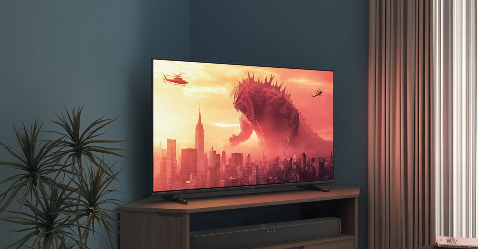 A Philips TV on a corner stand displays a Godzilla movie