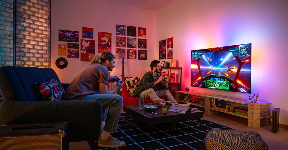 Two people enthusiastically play a space-themed video game in a cozy, colorful living room