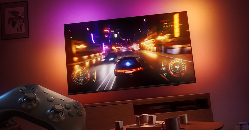 A racing video game is displayed on a Philips Ambilight TV in a dimly lit room