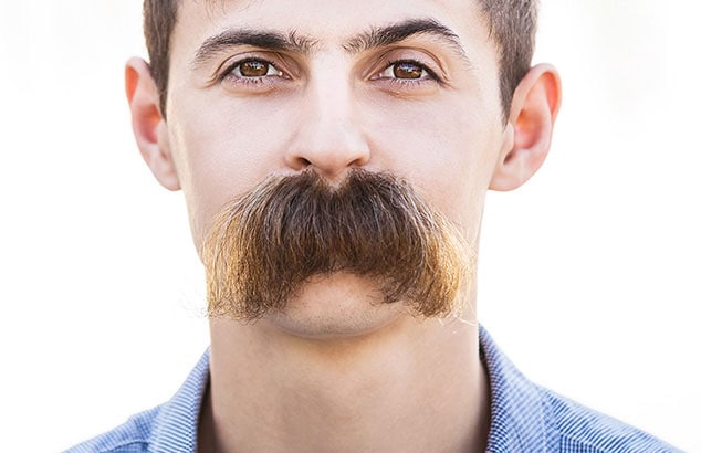 A man with a big brown walrus moustache looking directly into the camera.