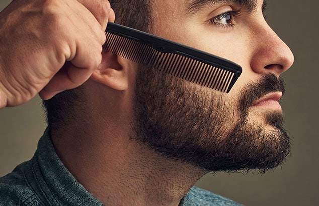 Side-profile of man with full beard having his cheek hairs combed into place.