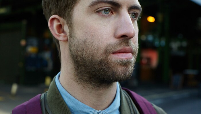 Close-up of a man with a three-day beard looking sideways at the camera.