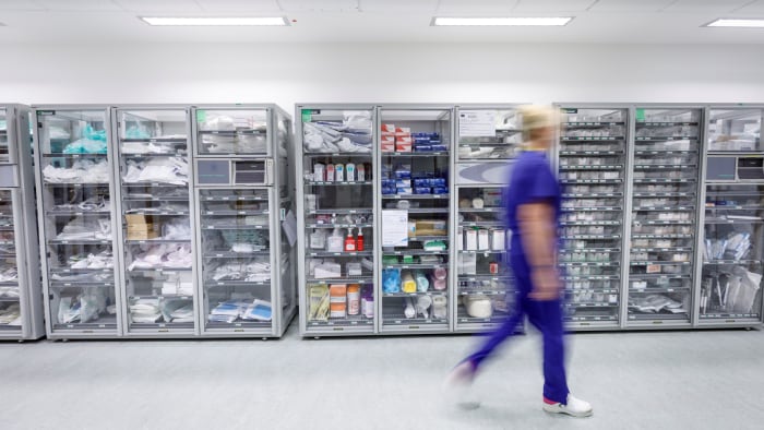 Healthcare professional walking past consumables storage units