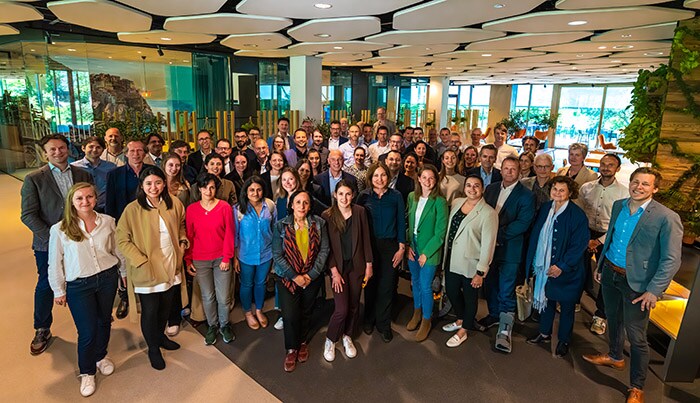 Image shows a photo of the   IMAGIO partners meet for the kick-off with a group of colleagues standing in a colourful office.